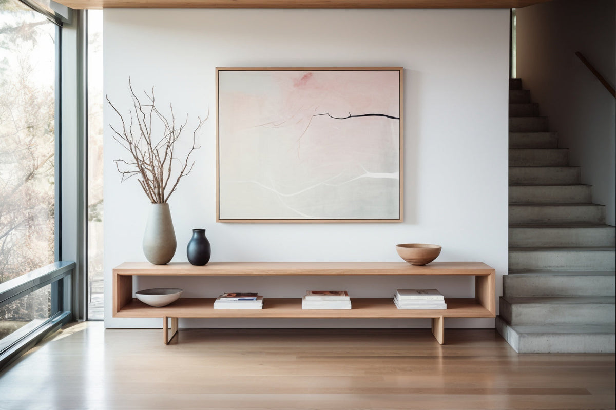 Modern minimalist living room with neutral tones, featuring a light wood media console, abstract art, ceramic vases with dried branches, and natural light from large windows